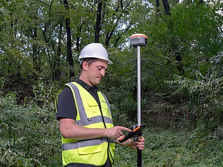 Agrimensor a utilizar o recetor CHCNAV i85 GNSS no terreno para efetuar levantamentos topográficos.